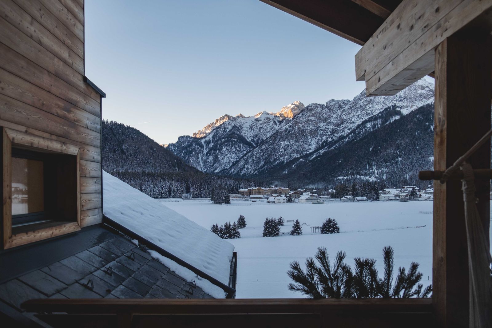 Snowy Teton valley seen from a timber lodge balcony at golden hour
