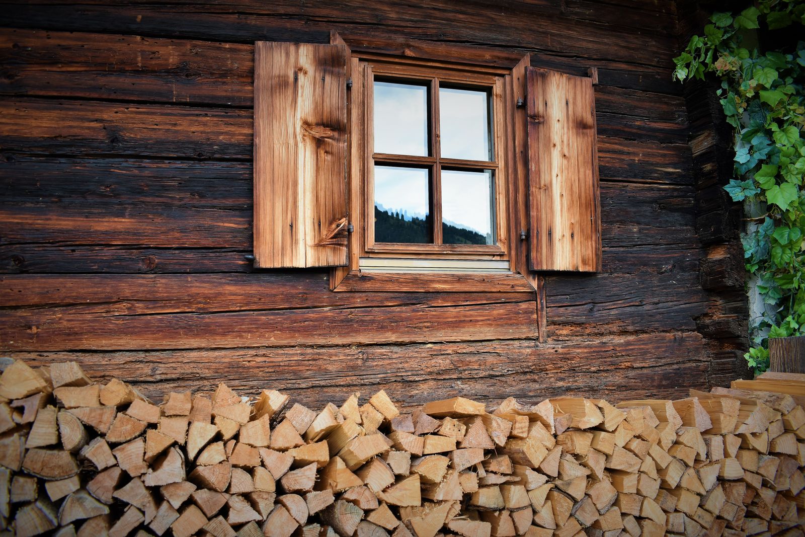 Rustic cabin wall with stacked firewood and timber windows